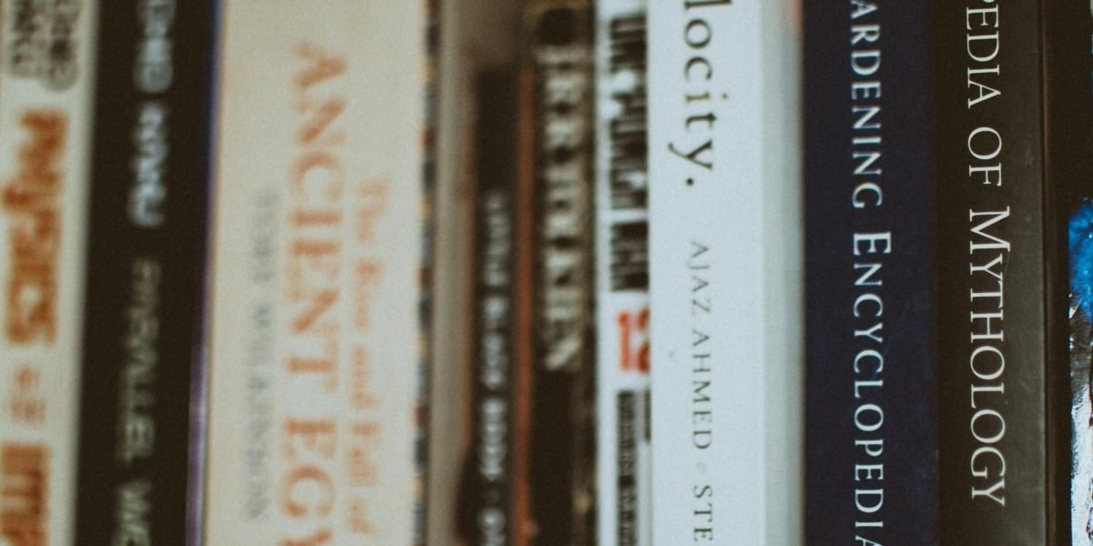 Stack of fantasy books on a shelf with warm lighting