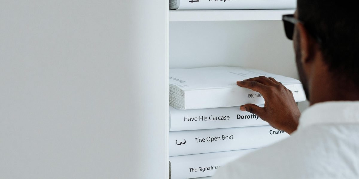 A person thoughtfully selecting books, curating their personal heated rivalry reading list.