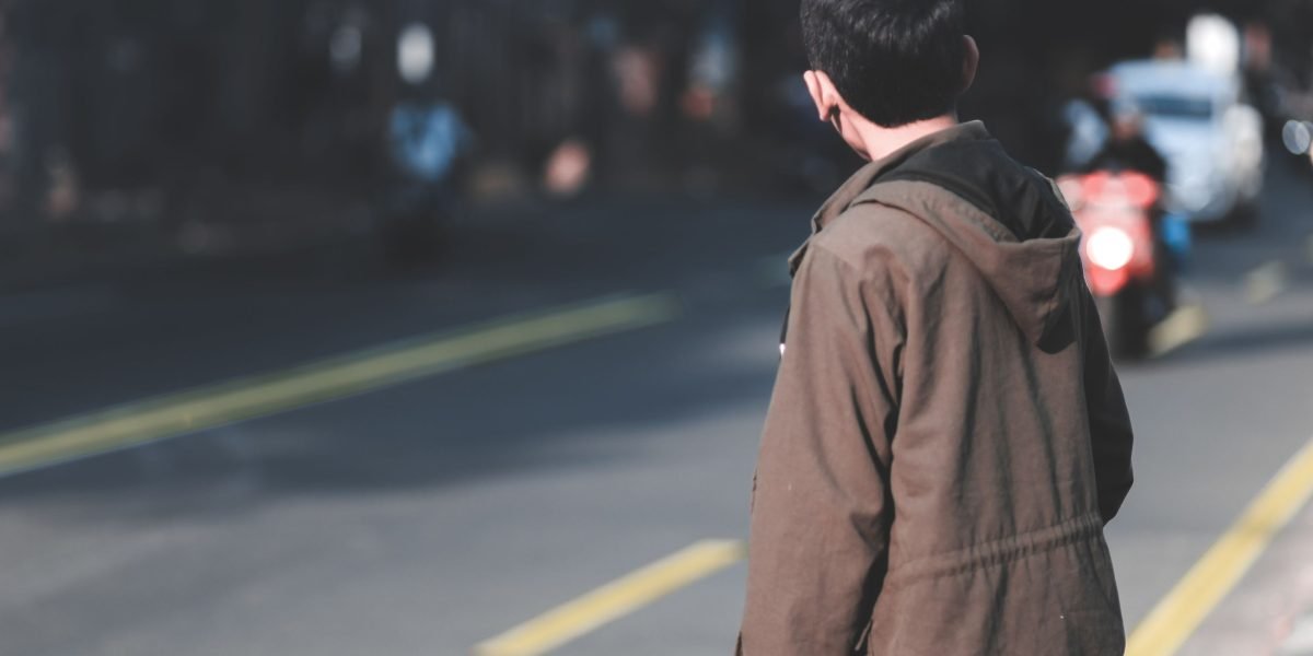 A pensive individual observing their surroundings, symbolizing an artist's keen eye for detail and human experience.