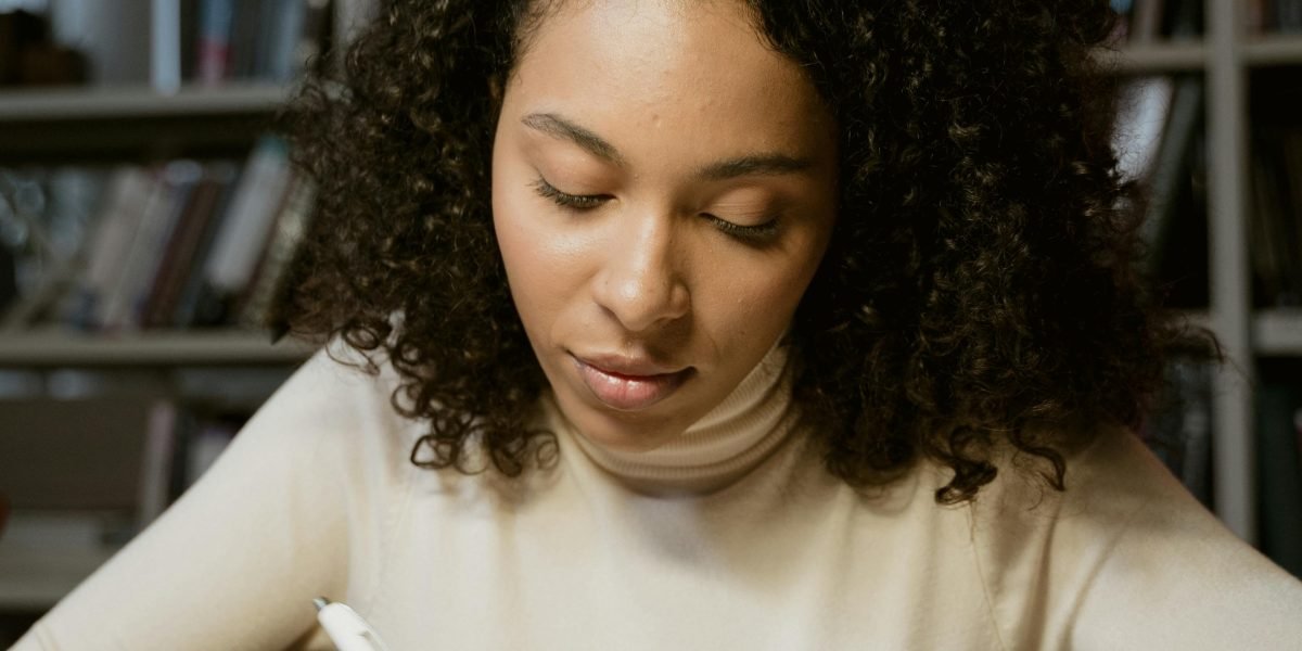 A woman writing intently in a quiet, historically-themed study, evoking the context of Emily Brontë's life.
